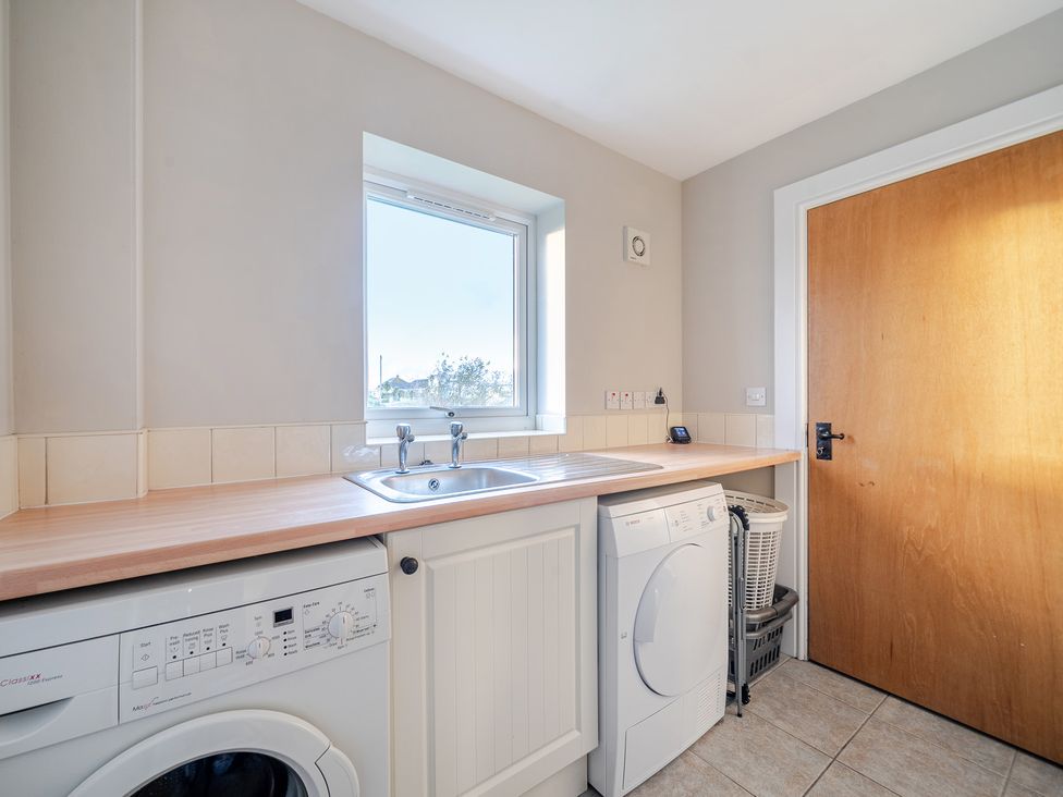 A utility room with a washing machine and sink at Curragho in Trearddur Bay
