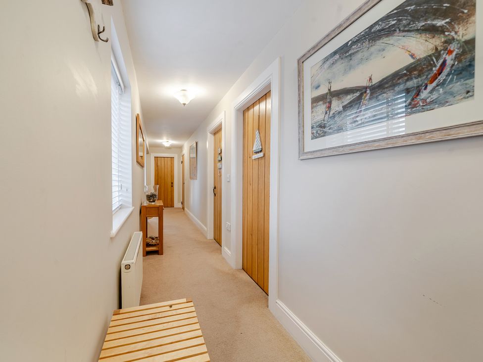 A hallway with doors and a table at Curragho in Trearddur Bay