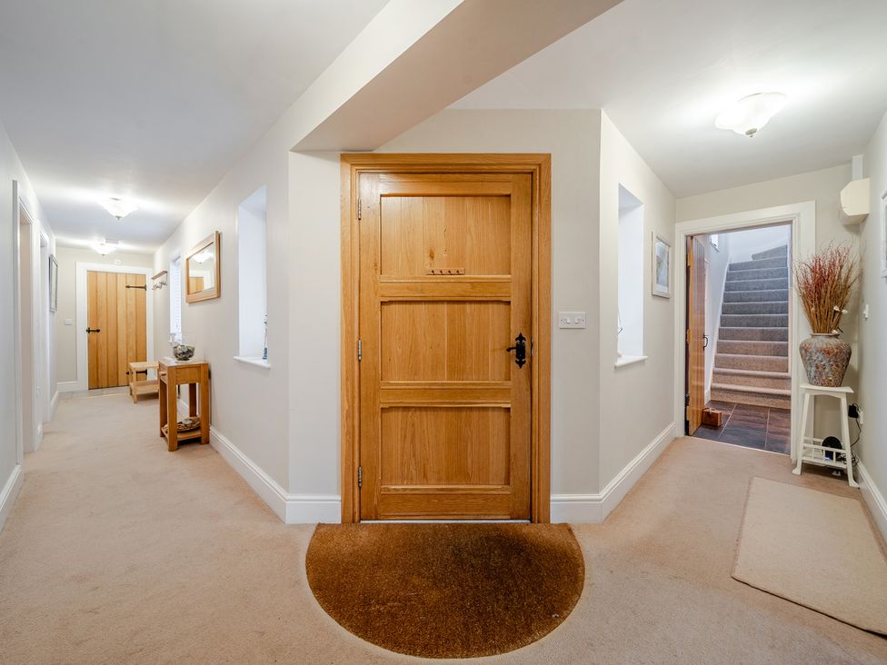 A hallway with a front door and stairs at Curragho in Trearddur Bay