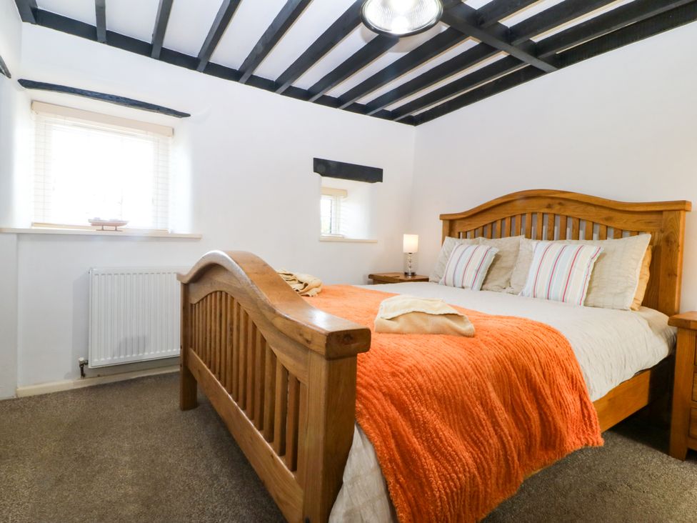 A bedroom with a wooden bed and windows at Farm Cottage in Cemaes Bay