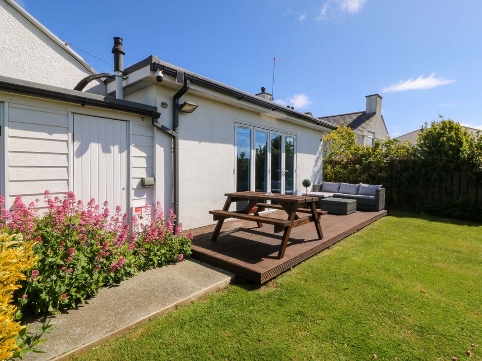 A house with a patio and flowerbed at Farm Cottage in Cemaes Bay