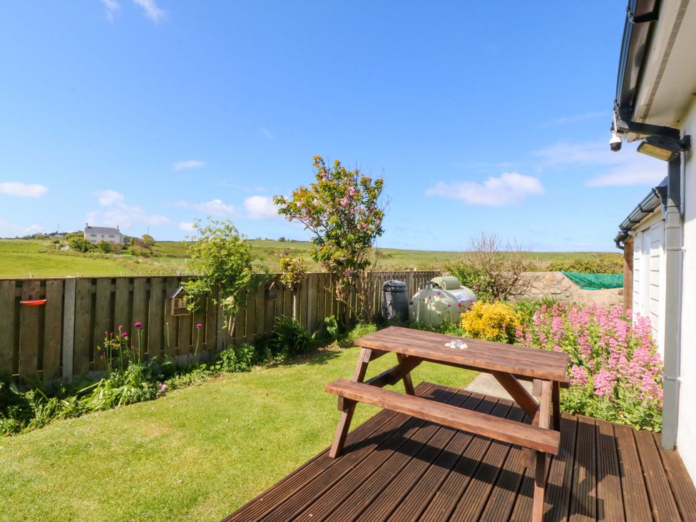 A garden with a picnic table and flowers at Farm Cottage in Cemaes Bay