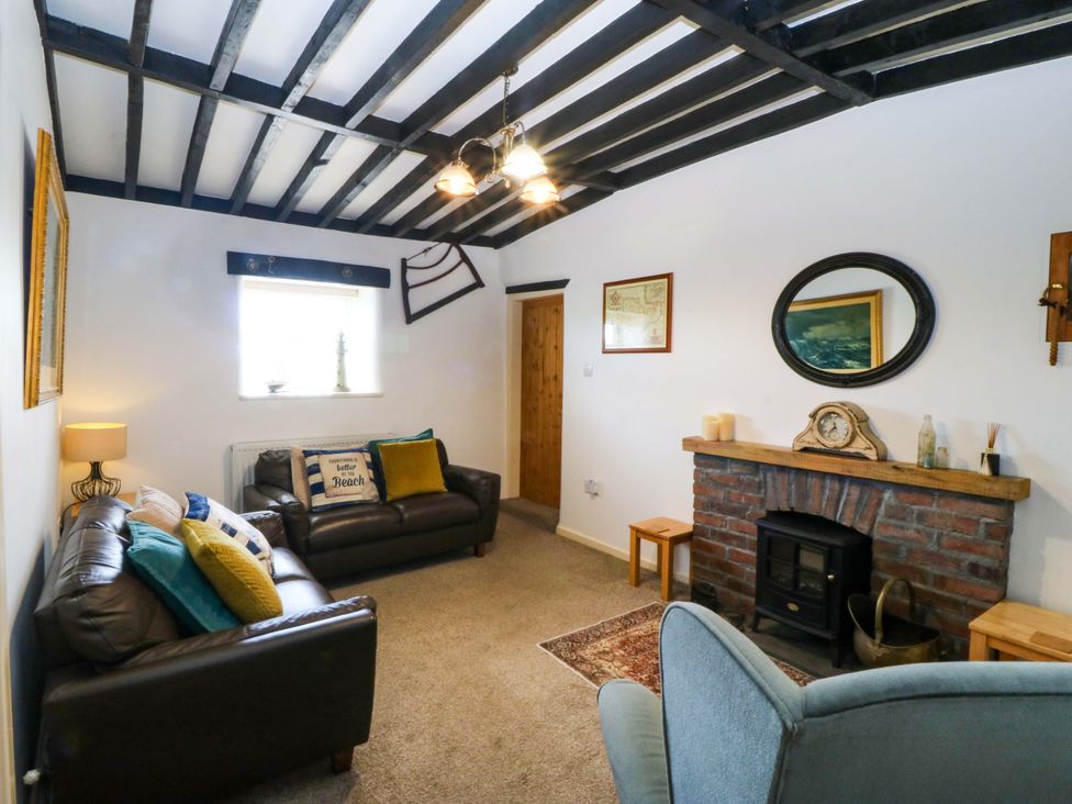 A living room with sofas and a fireplace at Farm Cottage in Cemaes Bay