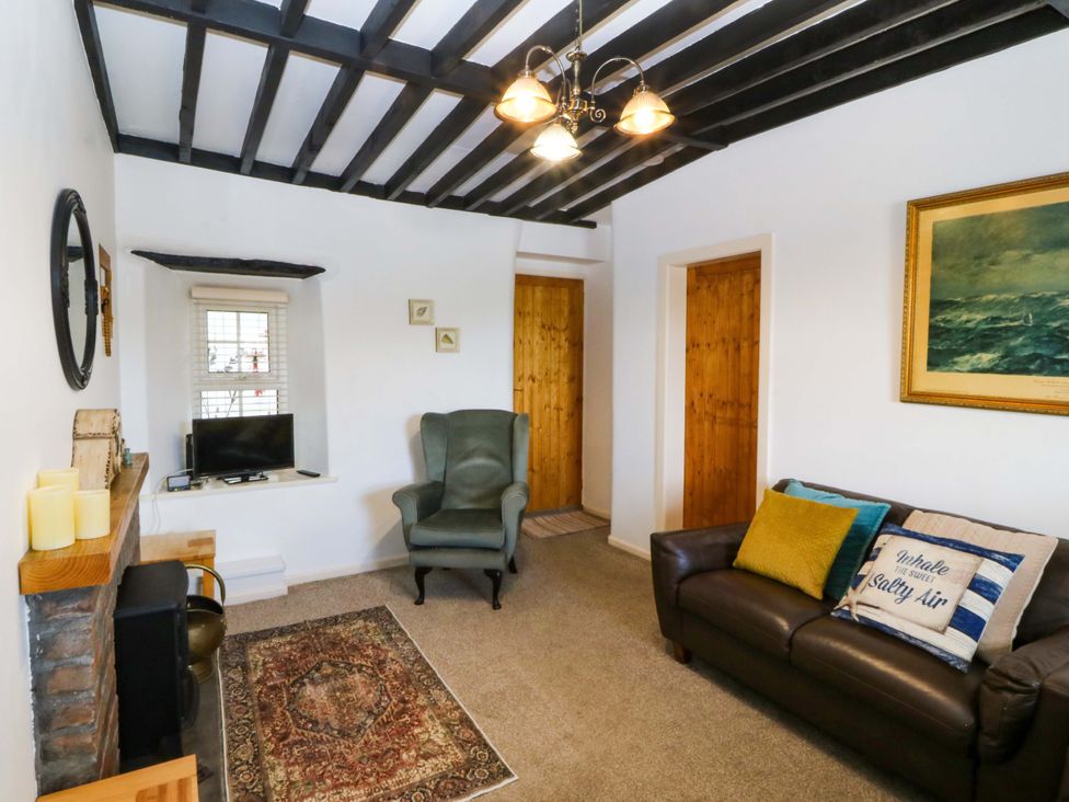 A living room with a sofa and television at Farm Cottage in Cemaes Bay