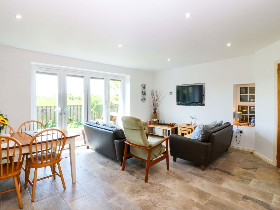 A living room with a sofa and dining area at Farm Cottage in Cemaes Bay