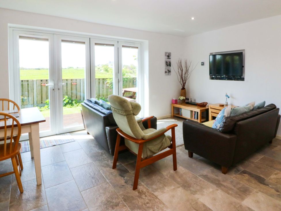 A living room with sofas and a dining table at Farm Cottage in Cemaes Bay