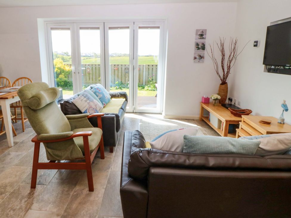 A living room with a sofa and chairs at Farm Cottage in Cemaes Bay