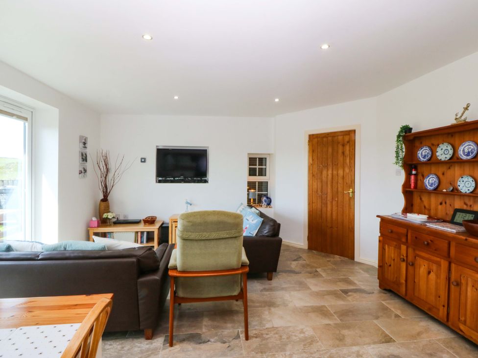 A living room with a sofa and television at Farm Cottage in Cemaes Bay