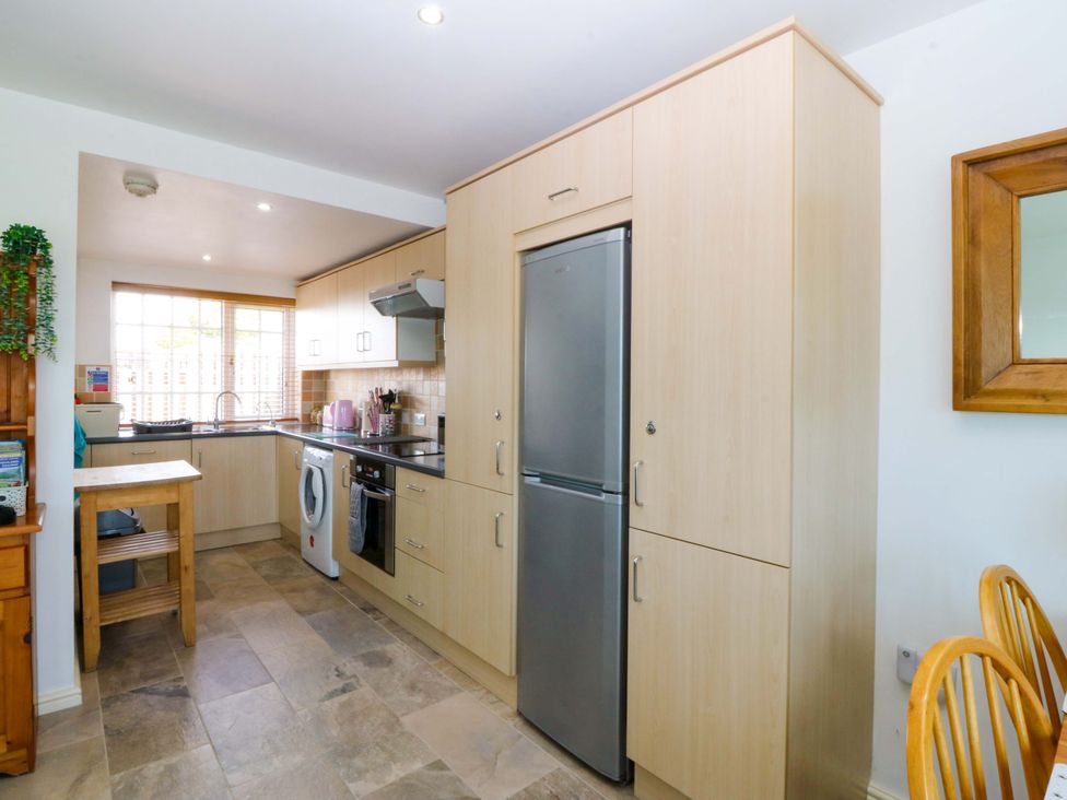 A kitchen with appliances and dining area at Farm Cottage in Cemaes Bay