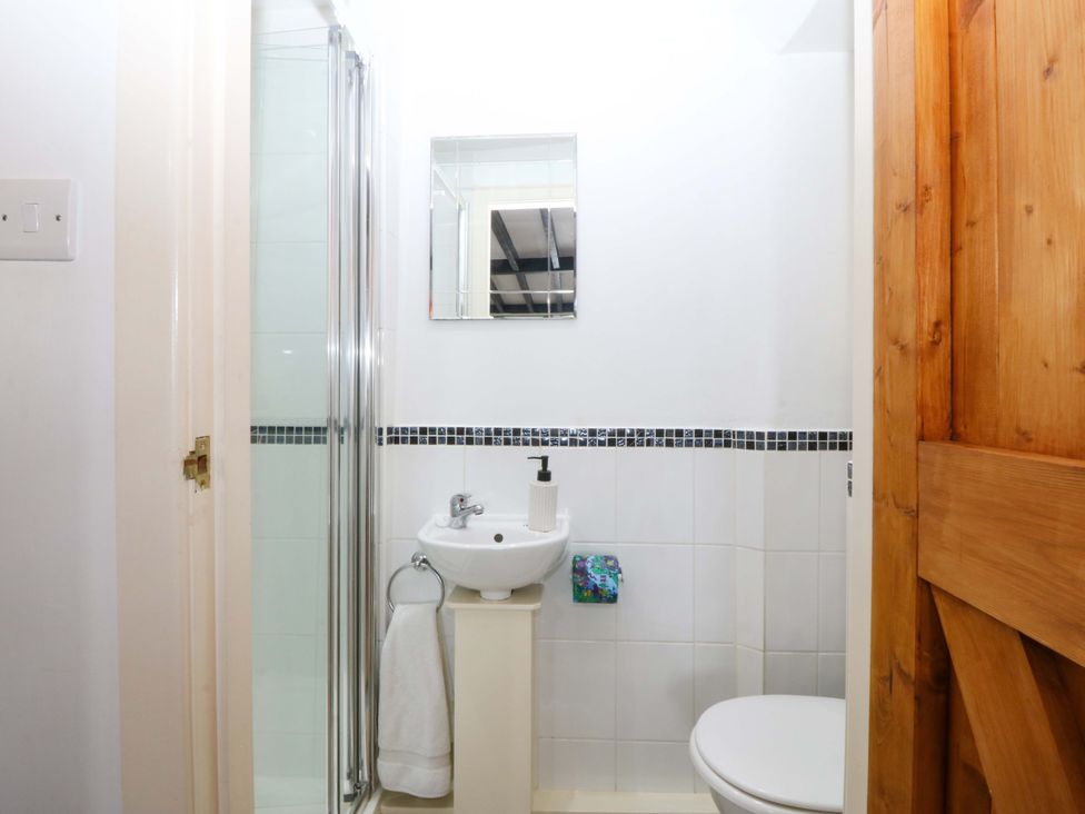 A bathroom with a shower, sink, and toilet at Farm Cottage in Cemaes Bay