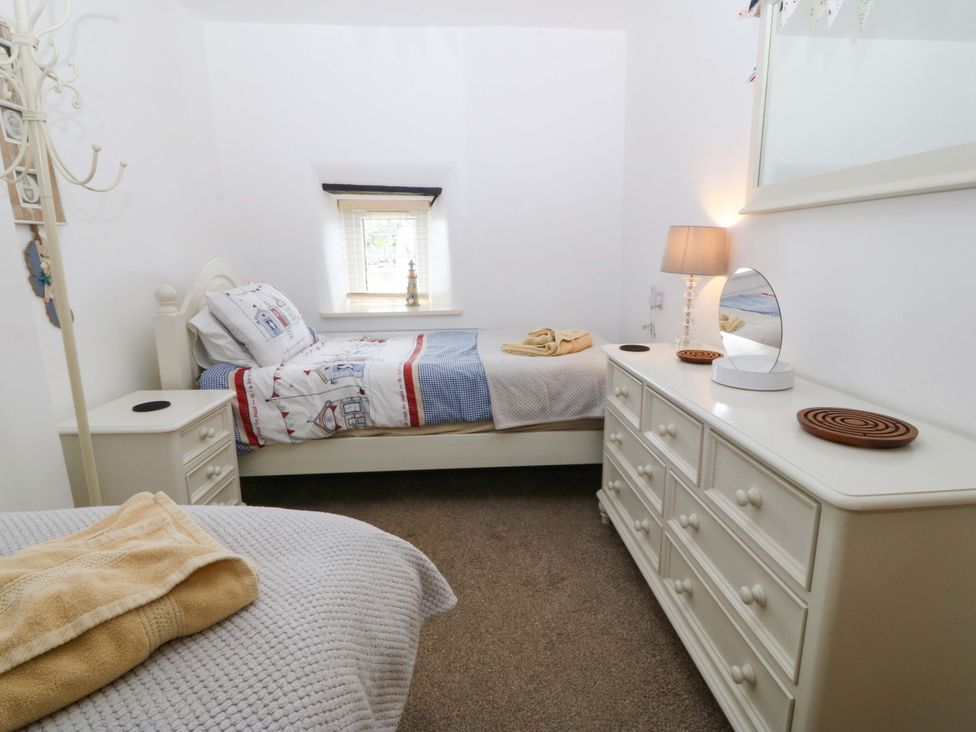 A bedroom with two beds and a dresser at Farm Cottage in Cemaes Bay