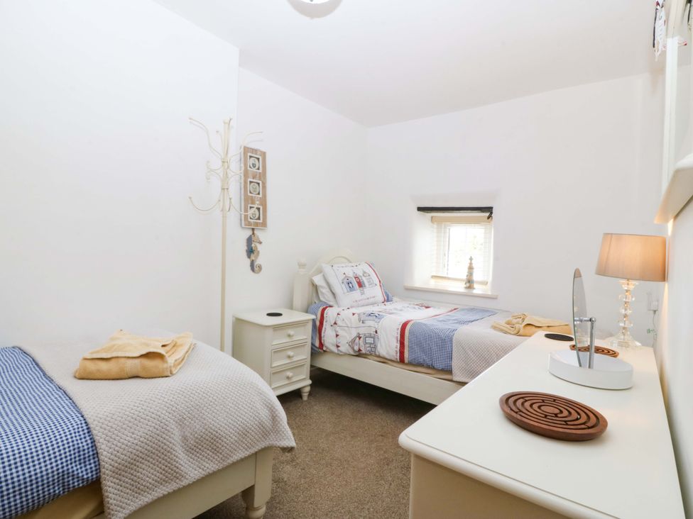 A bedroom with two beds and a lamp at Farm Cottage in Cemaes Bay