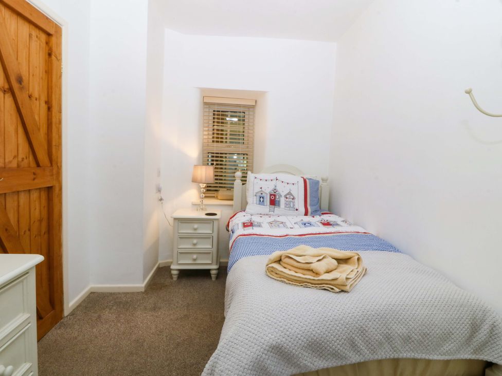 A bedroom with a single bed and bedside table at Farm Cottage in Cemaes Bay