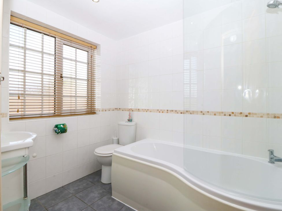 A bathroom with a bathtub, toilet, and sink at Farm Cottage in Cemaes Bay