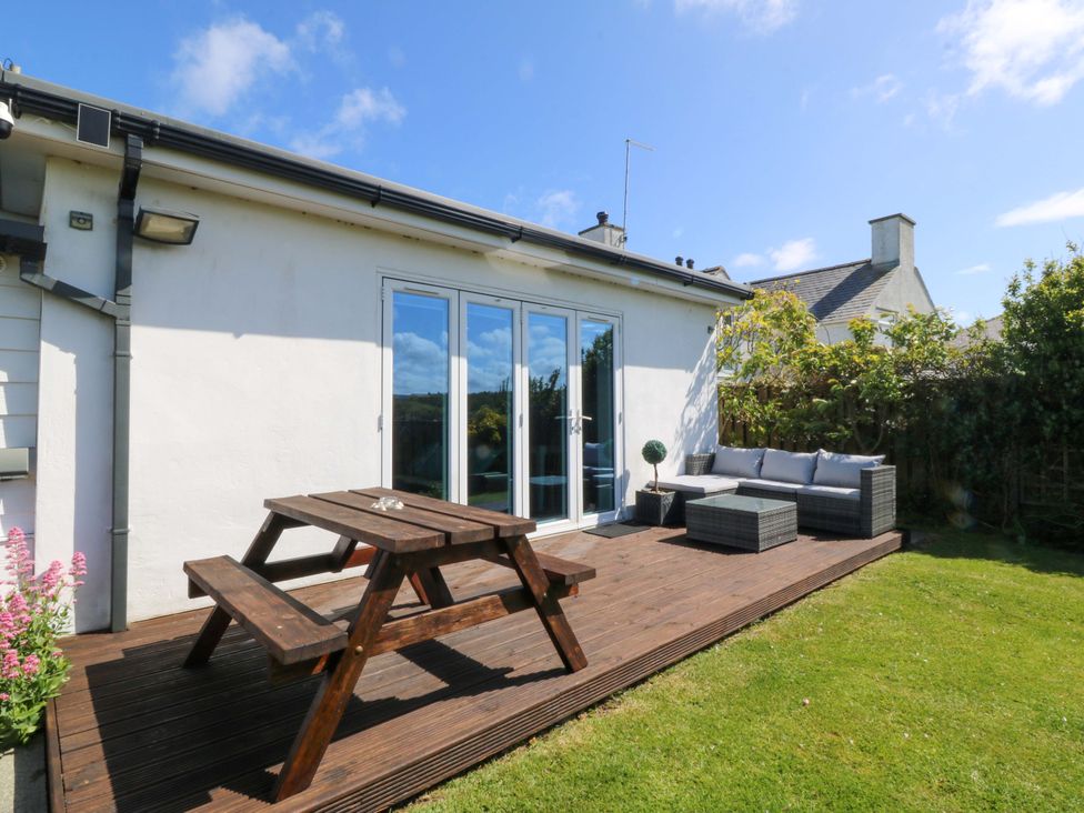 A garden with a table and bench on a deck at Farm Cottage in Cemaes Bay