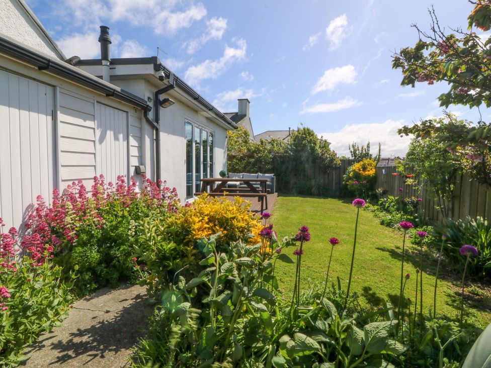 A garden with flowers and a wooden deck at Farm Cottage in Cemaes Bay