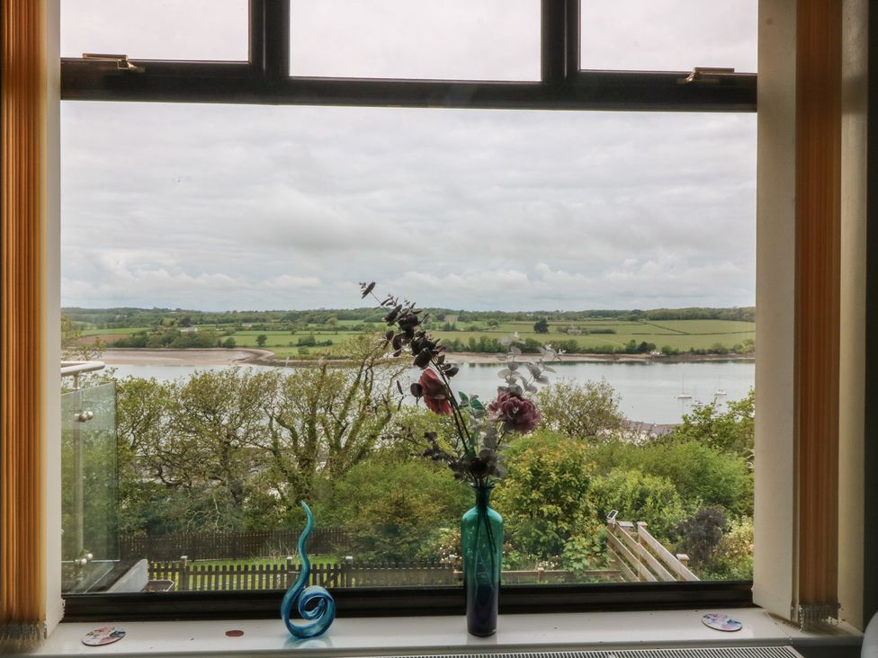 A window with a vase and flowers overlooking a landscape at Gwylan Uchaf in Y Felinheli