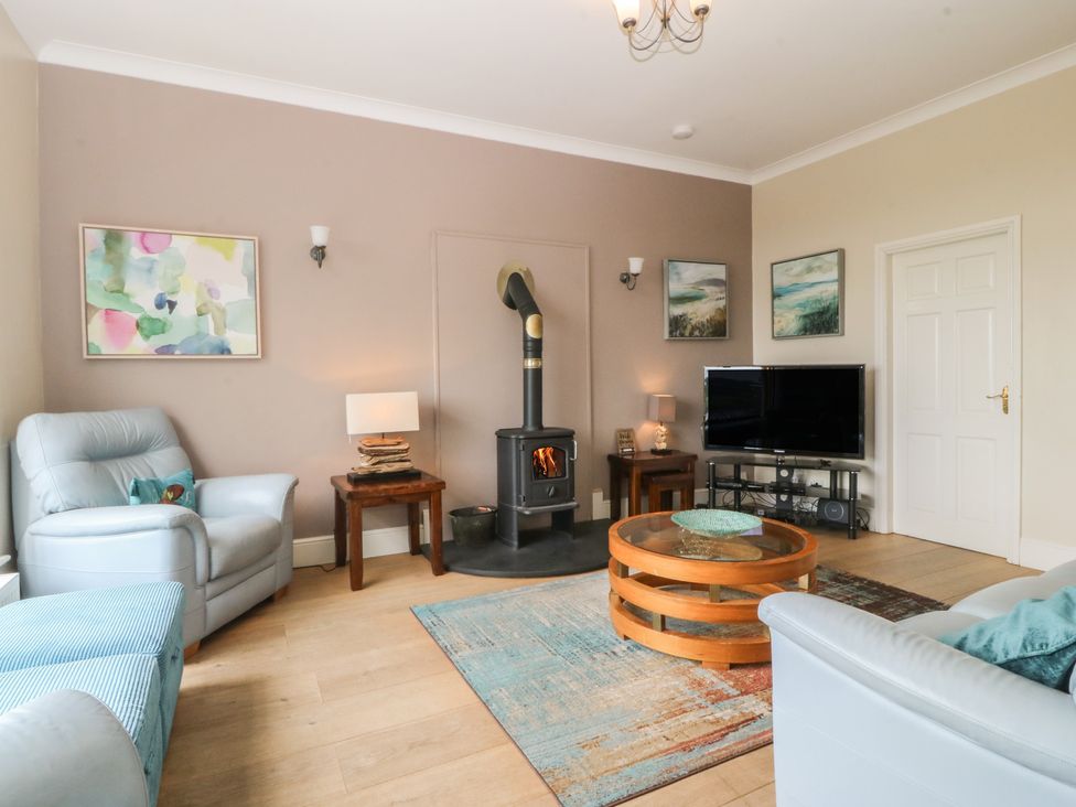 A living room with a stove and television at Gwylan Uchaf in Y Felinheli