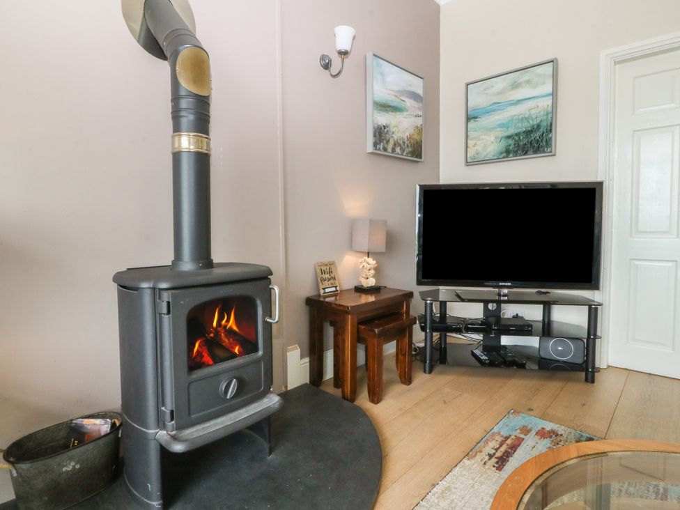 A living room with a wood stove and television at Gwylan Uchaf Y Felinheli