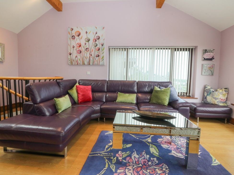 A living room with a purple sofa and a coffee table at Gwylan Uchaf in Y Felinheli