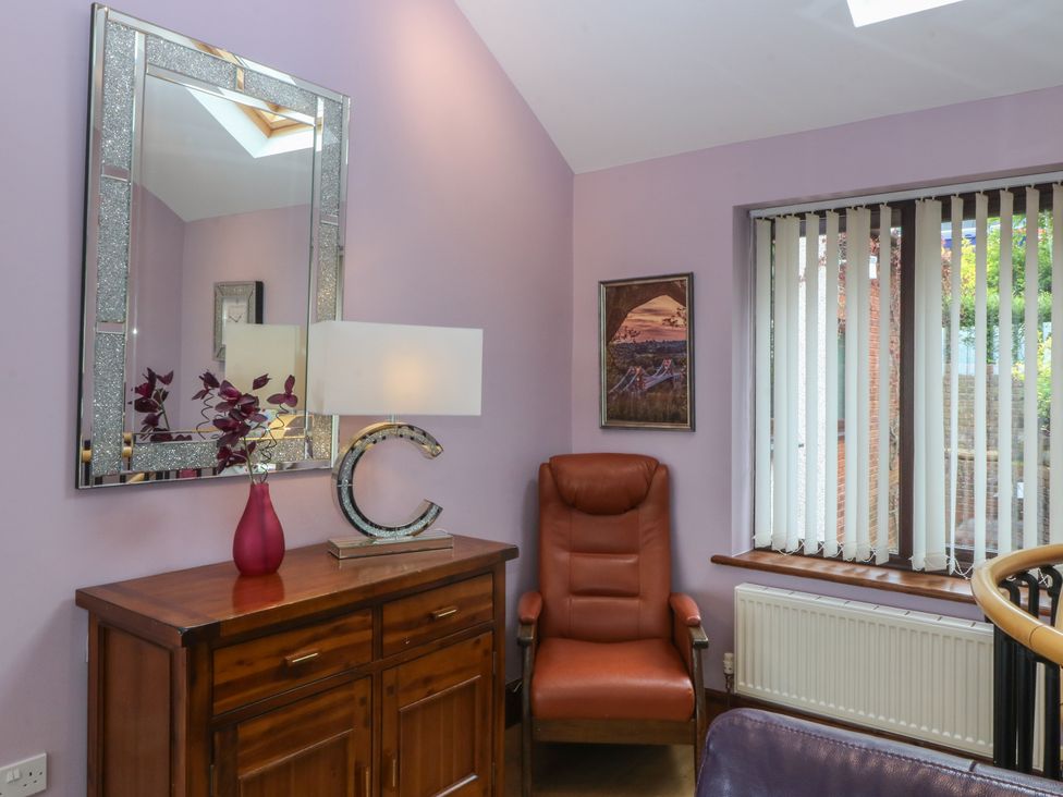A living room with a chair and lamp at Gwylan Uchaf in Y Felinheli