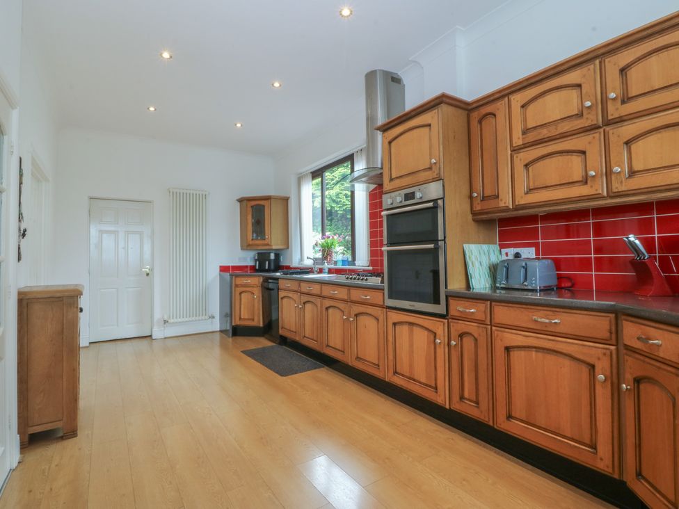 A kitchen with wooden cabinets and appliances at Gwylan Uchaf in Y Felinheli