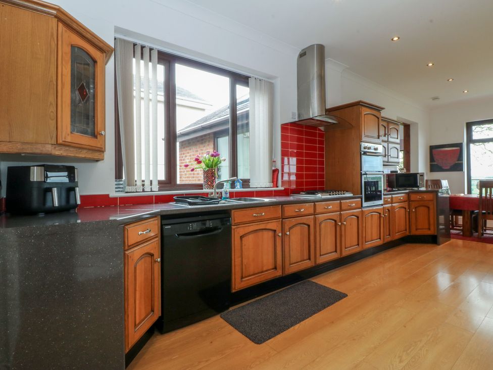 A kitchen with wooden cabinets and appliances at Gwylan Uchaf Y Felinheli