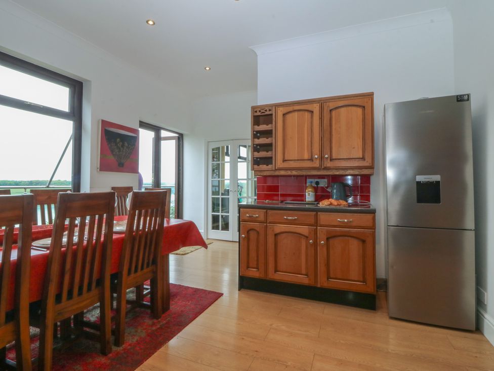 A kitchen with a dining table and refrigerator at Gwylan Uchaf Y Felinheli