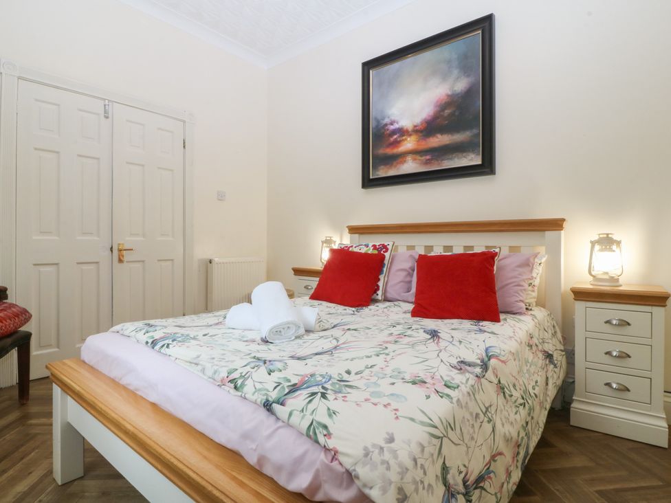 A bedroom with a bed and bedside tables at Gwylan Uchaf in Y Felinheli