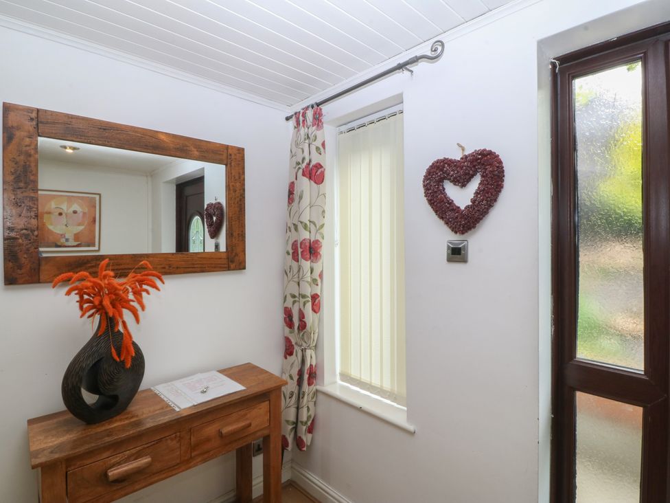 A hallway with a mirror and a console table at Gwylan Uchaf Y Felinheli