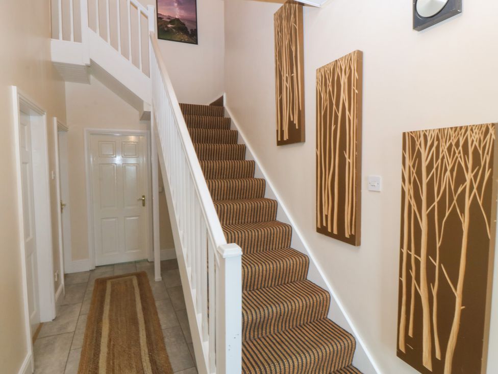 A staircase and hallway with wall art at Gwylan Uchaf in Y Felinheli