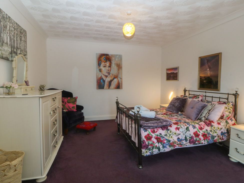 A bedroom with a bed and dresser at Gwylan Uchaf in Y Felinheli