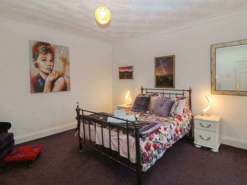A bedroom with a bed and paintings at Gwylan Uchaf in Y Felinheli