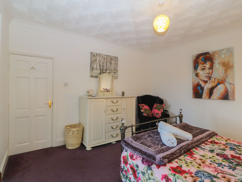 A bedroom with a bed and dressing table at Gwylan Uchaf Y Felinheli