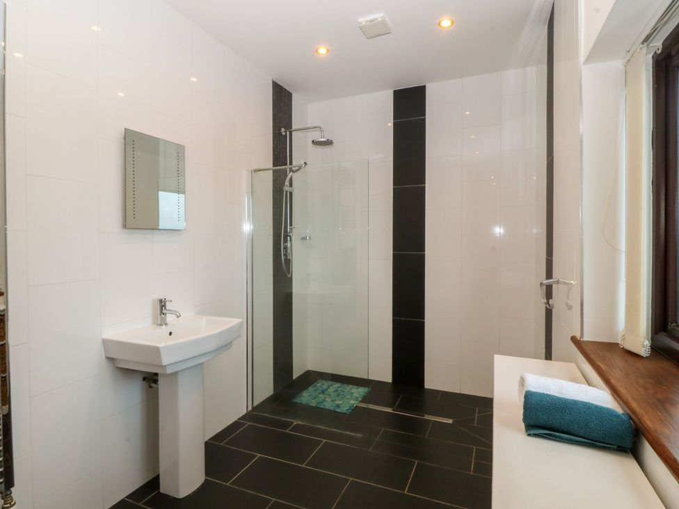A bathroom with sink, shower, and towel at Gwylan Uchaf Y Felinheli