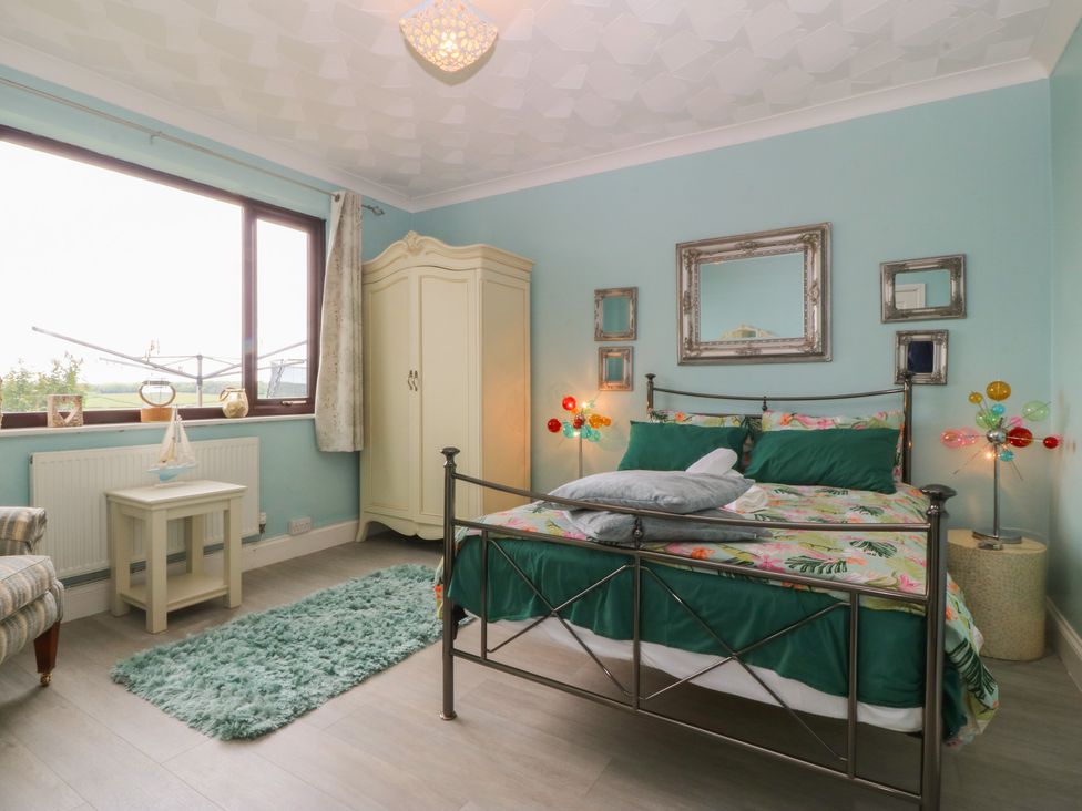 A bedroom with a bed and wardrobe at Gwylan Uchaf Y Felinheli