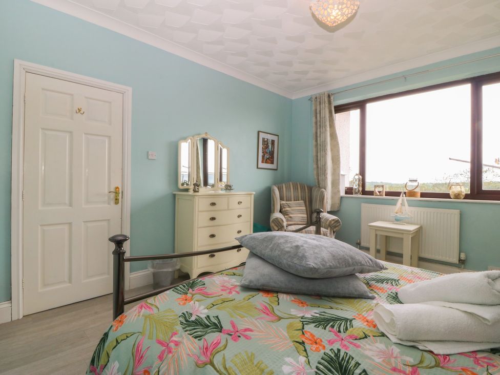 A bedroom with a bed and dresser at Gwylan Uchaf Y Felinheli
