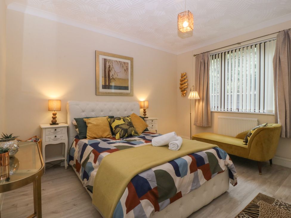 A bedroom with a bed and sofa at Gwylan Uchaf in Y Felinheli