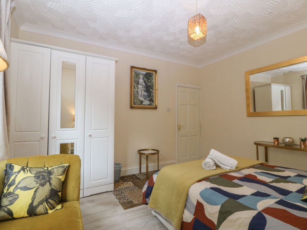A bedroom with a bed and wardrobe at Gwylan Uchaf in Y Felinheli
