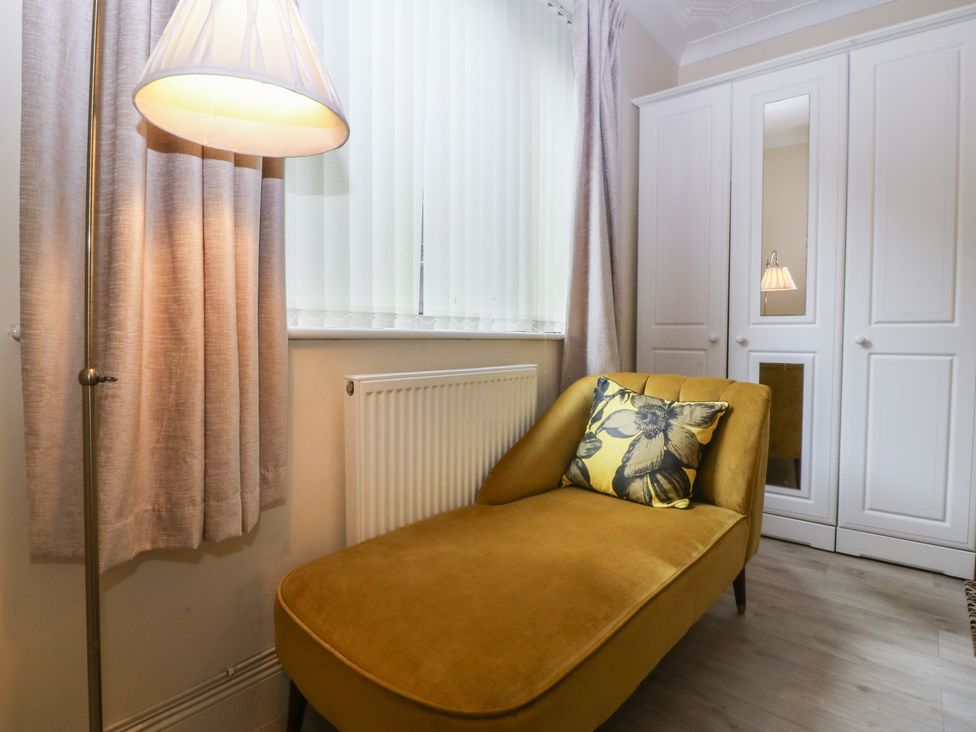 A living room with a chaise lounge and lamp at Gwylan Uchaf in Y Felinheli