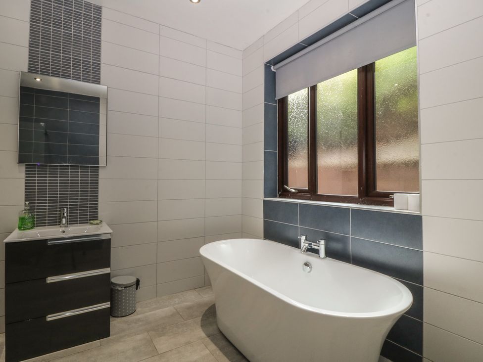 A bathroom with a bathtub and a vanity at Gwylan Uchaf Y Felinheli