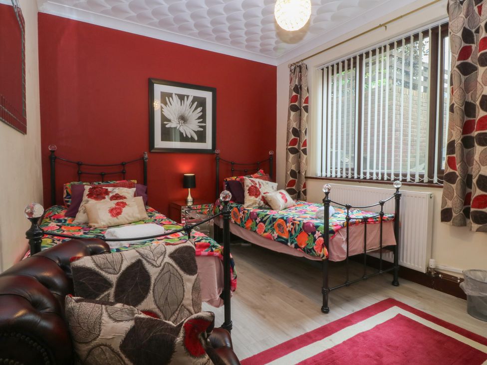 A bedroom with two beds and a bedside table at Gwylan Uchaf Y Felinheli