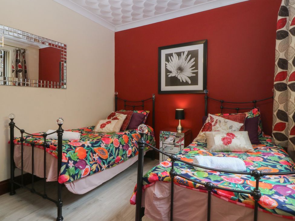 A bedroom with two beds and a mirror at Gwylan Uchaf in Y Felinheli