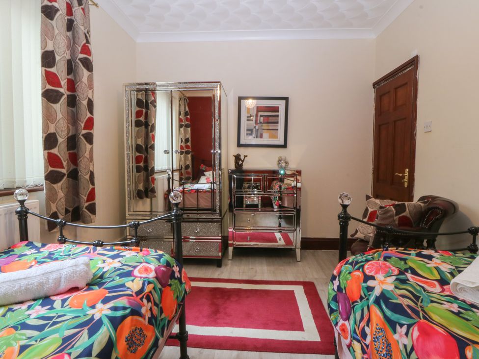 A bedroom with two beds and a mirror at Gwylan Uchaf Y Felinheli