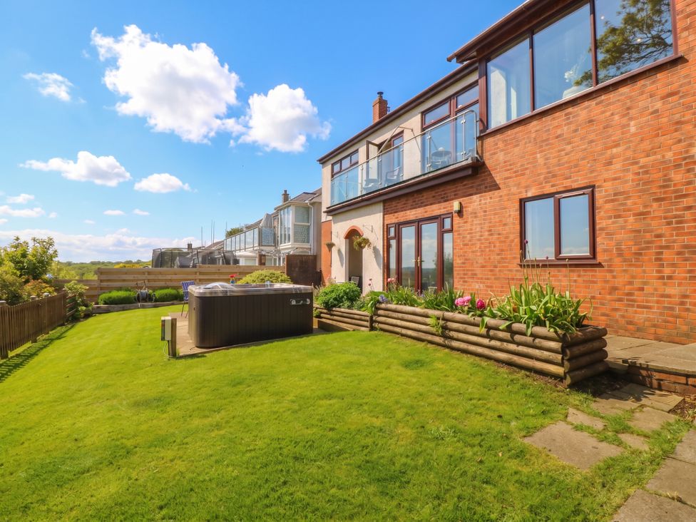 An outdoor garden area with a hot tub and flower bed at Gwylan Uchaf Y Felinheli