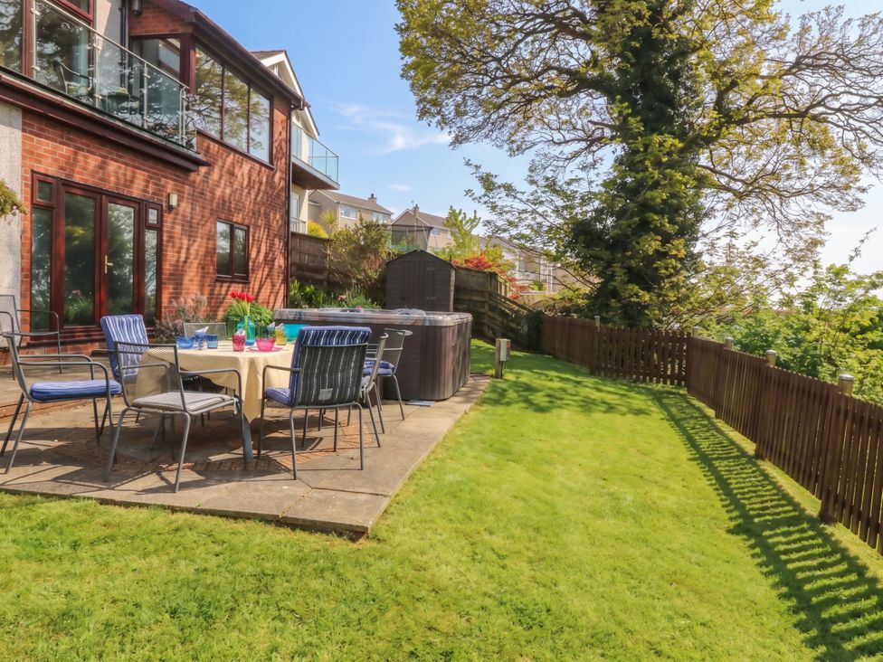 A garden with table and chairs beside a hot tub at Gwylan Uchaf Y Felinheli