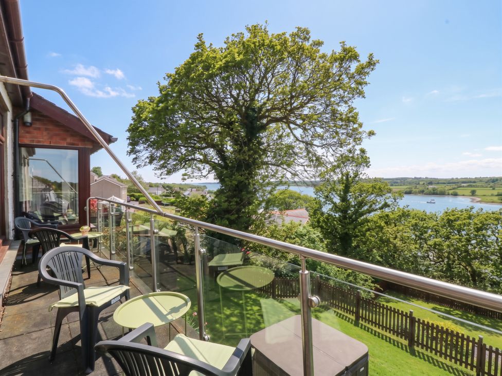 An outdoor area with chairs and a table overlooking a waterway at Gwylan Uchaf Y Felinheli