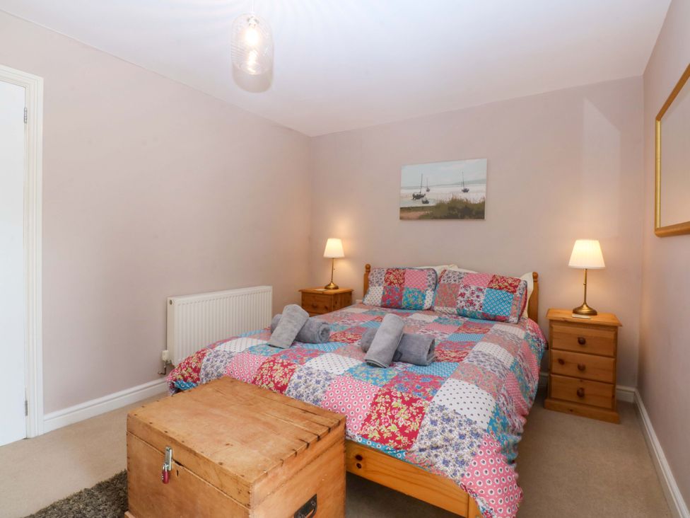 A bedroom with a bed and nightstands at Machlud Ynys Y Felinheli