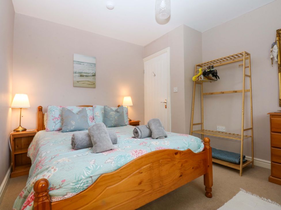 A bedroom with a bed and a storage rack at Machlud Ynys, Y Felinheli