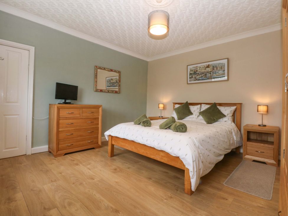 A bedroom with a bed and dresser at Menai Cottage in Brynsiencyn